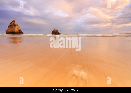 Ciel rose au coucher du soleil sur les falaises et la plage de sable fin entouré par la mer claire Praia Dos Tres Irmaos Portimao Algarve Portugal Europe Banque D'Images