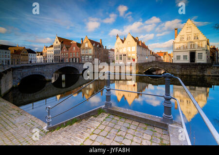 Vue sur les bâtiments typiques reflétée sur le canal au lever du soleil d'une terrasse sur le quai Bruges Flandre occidentale belgique europe Banque D'Images