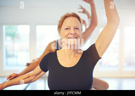 Hauts femme balletdancer avec permanent jusqu'à la main et à la caméra à tout en faisant de l'exercice dans la classe. Banque D'Images