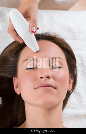 Close-up de la personne donnant la main à un traitement de microdermabrasion jeune femme dans un centre de beauté Banque D'Images