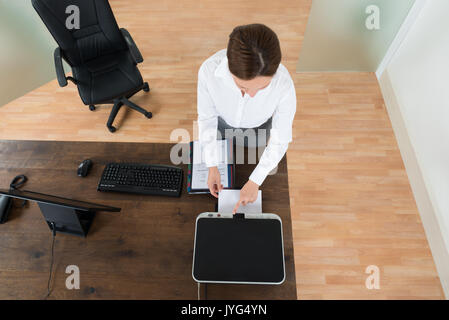 High Angle View of Young Businesswoman Using Printer At Desk In Office Banque D'Images