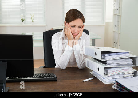 Souligné Young Businesswoman Looking At Pile de Folders In Office Banque D'Images