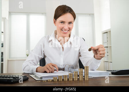 Close-up of Happy Businesswoman plaçant pile de pièces de monnaie Banque D'Images