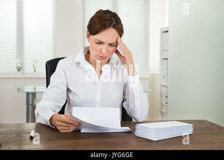 Souligné Businesswoman Looking At Document At Desk In Office Banque D'Images