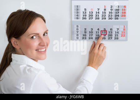 Close-up of Young Businesswoman plaçant marque rouge sur la date du calendrier Banque D'Images