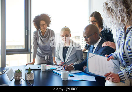 Groupe d'affaires axé autour de leur gestionnaire permanent assis à une table de réunion du bureau de l'examen des graphiques et de la paperasserie Banque D'Images