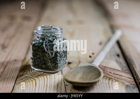 Ajoutez du piquant dans un pot sur une table en bois, cuillère en bois, fond noir Banque D'Images