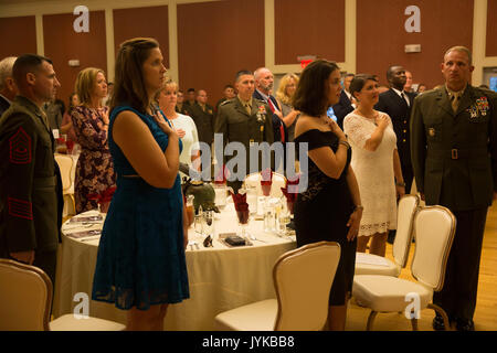 Participants au garde à vous tandis que d'autres la main sur le coeur pendant l'hymne national pour un dîner d'anniversaire pour 6e Régiment de Marines à Camp Lejeune, en Caroline du Nord, le 18 août, 2017. Les Marines et les marins du 6e Régiment de Marines célèbrent leur 100e anniversaire depuis le régiment a été créé en 1917. Le régiment a mené des opérations dans des endroits tels que le Liban, la Syrie, et a participé à des batailles célèbres tels que Belleau Wood, Tarawa, et de Saipan. (U.S. Marine Corps photo de Pvt. Nicolas Guevara) Banque D'Images