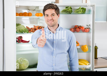 Portrait de bel homme Armcrossed avec debout devant ouvrir un réfrigérateur Banque D'Images