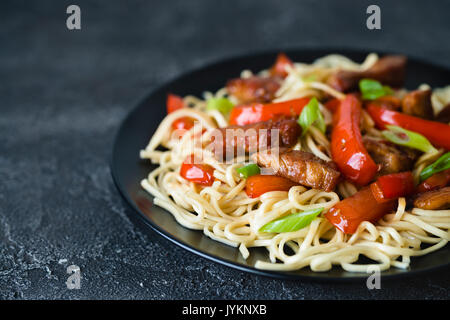 Sauté de porc épicé Szechuan avec poivron rouge et oignon. Les produits alimentaires chinois ou de la cuisine asiatique concept sur fond sombre. Selective focus Banque D'Images
