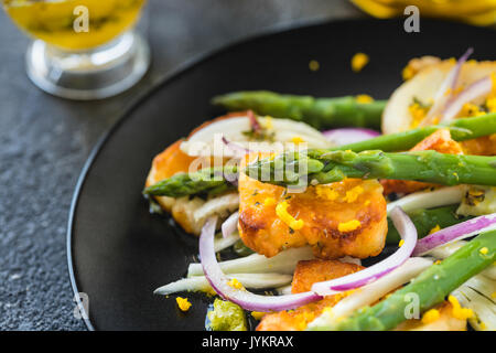 Frites salade d'asperges, halloumi et le zeste d'orange. Close up. Arrière-plan de béton foncé Banque D'Images