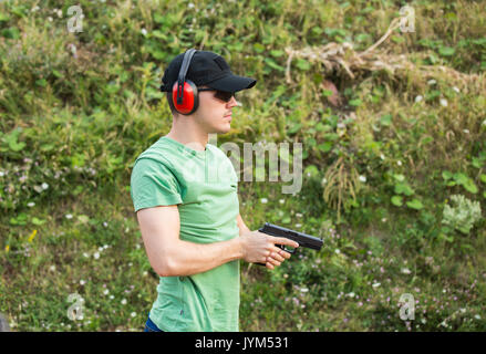 Beau jeune homme musclé à la cible sur l'ennemi sur la formation permanente et de bataille à coups de pistolet Glock dans ses mains prise ferme sur l'equi Banque D'Images