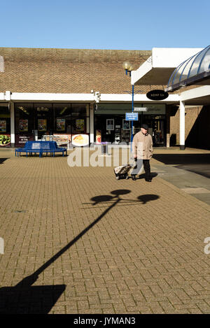 Seul pensionné pao tirant un chariot au moyen d'un seul guide centre commercial vide dans la journée dans le soleil à l'extérieur Banque D'Images