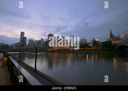 Une longue exposition photo de la rivière Yarra, la gare de Flinders Street, un groupe de bâtiments, et la passerelle de Southbank. Banque D'Images