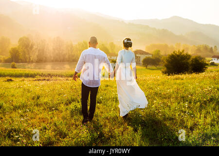 Couple en train de marcher sur le terrain avec vue sur le coucher de soleil romantique Banque D'Images