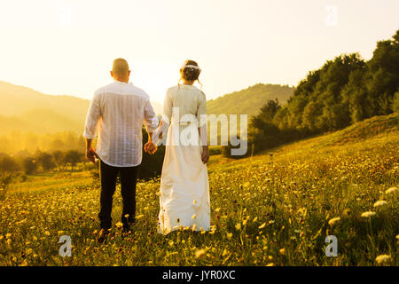 Couple en train de marcher sur le terrain avec vue sur le coucher de soleil romantique Banque D'Images