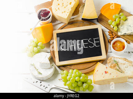 Fromage servi avec du raisin, de la confiture, du pain et des noix sur planche de bois. Banque D'Images