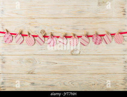 Décoration de Pâques. Oeufs en papier avec un ruban rose sur un fond en bois clair. Focus sélectif. Banque D'Images