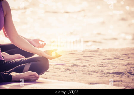 Filtre vintage de Close up mains de maître de yoga assis faisant part des Mudras et médite sur la plage au littoral, calmer et détendre et bien-être concept,healt Banque D'Images
