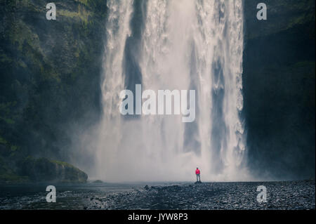 Le sud de l'Islande. L'homme se tient au-dessous de la cascade de Skogafoss. Banque D'Images