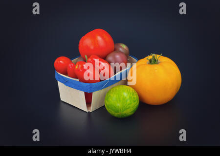 Assortiment de légumes bio tomates colorées sur fond noir Banque D'Images