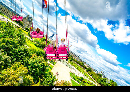 Les couples navigue dans les airs au-dessus des jardins des Tuileries lors du tour des chaises Swinging. Banque D'Images