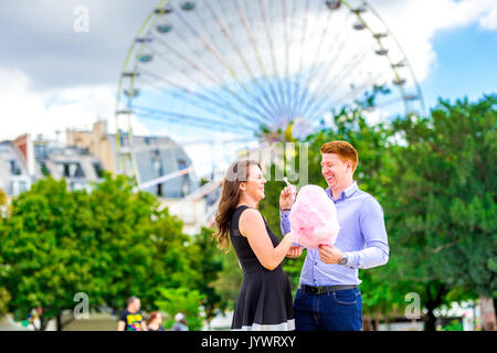 Un jeune couple amoureux ririt tout en mangeant des fée se lancer à l'extérieur de la Fète des Tuileries à Paris Banque D'Images