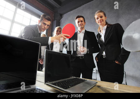 Les gens jouent au ping-pong sur la table de bureau avec des ordinateurs portables Banque D'Images