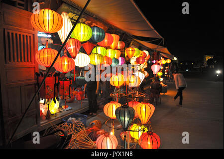 Lanternes allumées colorée à l'attention des passants à l'ancienne ville Hoi An, customer browsing shop et un autre client fixant ses chaussures. Hoi An. VIETNAM Banque D'Images