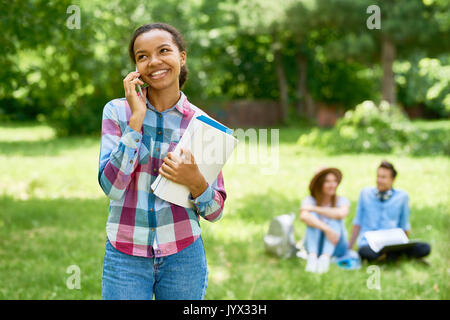 Cheerful étudiant africain parlant par téléphone Banque D'Images