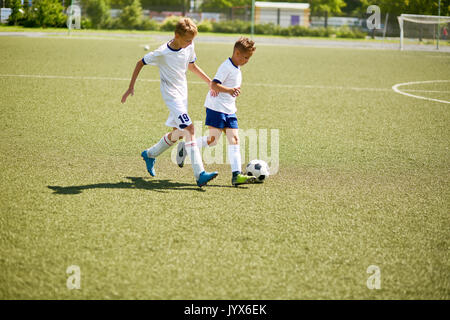 Deux garçons jouant au football sur terrain Banque D'Images