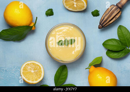 Le lait caillé de citron dans un bol en verre, de citrons frais, centrifugeuse, sur un fond bleu Banque D'Images