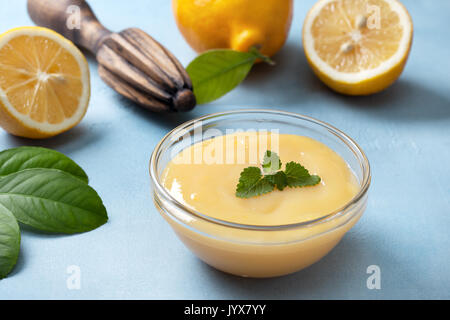 Le lait caillé de citron dans un bol en verre, de citrons frais, centrifugeuse, sur un fond bleu Banque D'Images