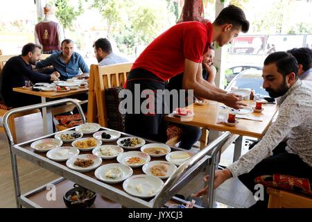 (170820) -- ANKARA, 20 août 2017 (Xinhua) -- Photo prise le 15 août 2017 montre un waiter serving plats de petit déjeuner à Van, Turquie. Le petit-déjeuner turc de Van, célèbre pour son goût délicieux et somptueux plats 20, tels que miel, fromage aux herbes, faites avec un mélange de différentes herbes uniques à la région ; martuga, faite avec de la farine, du beurre et des oeufs ; et kavut, faite avec du blé. Petit-déjeuner Van a remporté le record mondial Guinness avec 52 186 personnes a pris le petit déjeuner ensemble en 2015. (Xinhua/Qin Yanyang)(GL) Banque D'Images