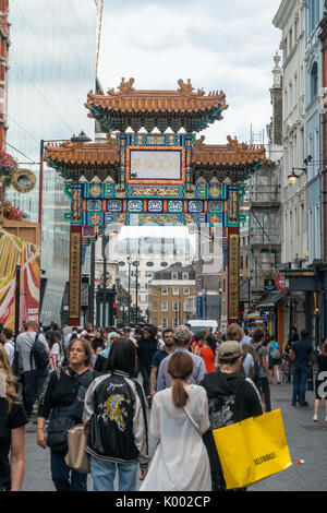 Foule de personnes marchant près de l'arche chinoise orientale au bout de Gerrard Street, Chinatown, Londres, Angleterre, Royaume-Uni Banque D'Images