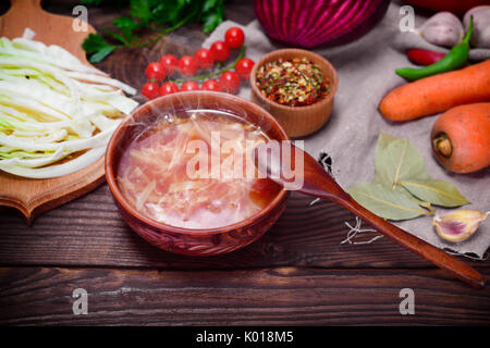 Le bortsch ukrainien traditionnel à une plaque brune au milieu de légumes et d'ingrédients sur une table en bois Banque D'Images