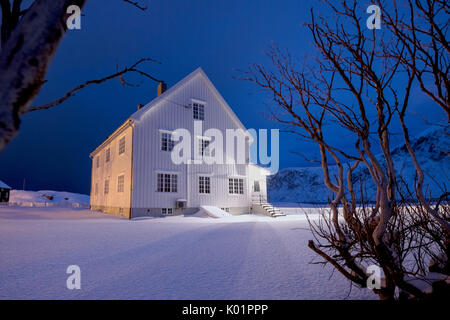 Lumières sur la maison en bois typique entouré de neige Flakstad Lofoten, Norvège du Nord Europe Banque D'Images