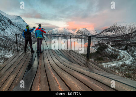 Photographes sur la plate-forme d'admirer les sommets enneigés reflétée dans la mer au coucher du soleil Bergsbotn Senja Troms County Norvège Europe Banque D'Images