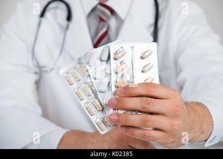 Au milieu du doctor holding blister against white background Banque D'Images
