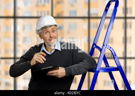 Contremaître à la maturité vers le haut. Contrôle de la construction ingénieur âgé avec presse-papiers, de bain, arrière-plan flou. Banque D'Images