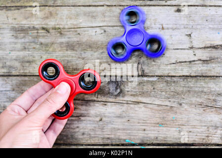 Fidget spinners dans fille Main sur fond de bois Banque D'Images