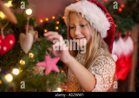 Petite fille pendaison quelques ornements de Noël Banque D'Images