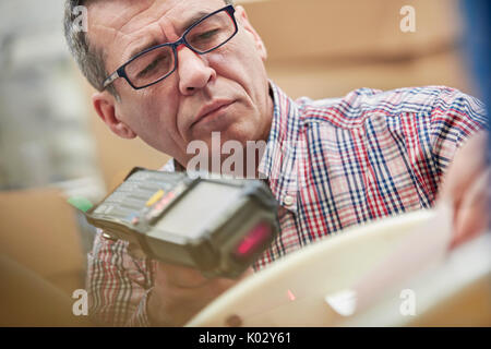 L'accent travailleur masculin à l'aide d'un lecteur de codes IR dans les fibres optiques warehouse Banque D'Images