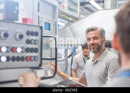 Portrait smiling male manager au panneau de commande de machines en usine Banque D'Images