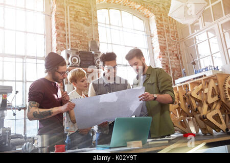 Designers examining blueprints in workshop Banque D'Images