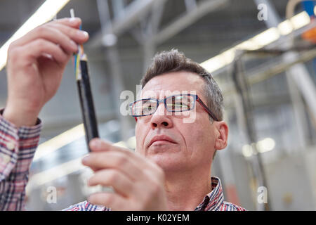 L'accent superviseur examinant les câbles à fibre optique en usine Banque D'Images