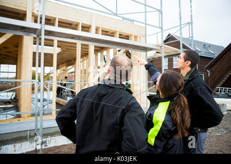 Female Carpenter pointant construction incomplète en position debout Banque D'Images