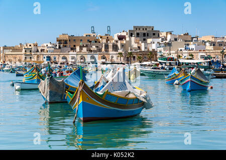 Les bateaux de pêche traditionnels flottant dans le port de Marsaxlokk, sur l'île de Malte. Les bateaux sont faits de bois et peint dans la tradition de couleurs. Banque D'Images