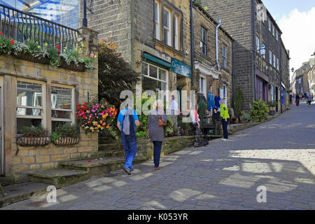 Les visiteurs jusqu'à pied de la rue principale pavée, Haworth, West Yorkshire, Angleterre, Royaume-Uni. Banque D'Images