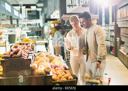 Jeune couple avec cell phone courses at market Banque D'Images